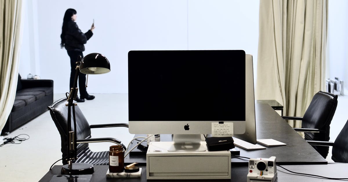 What is the location of photo used for Windows 10 lock screen? [duplicate] - Monitor of modern computer and instant photo camera placed on black table in modern workspace against female standing with smartphone near window with light curtains