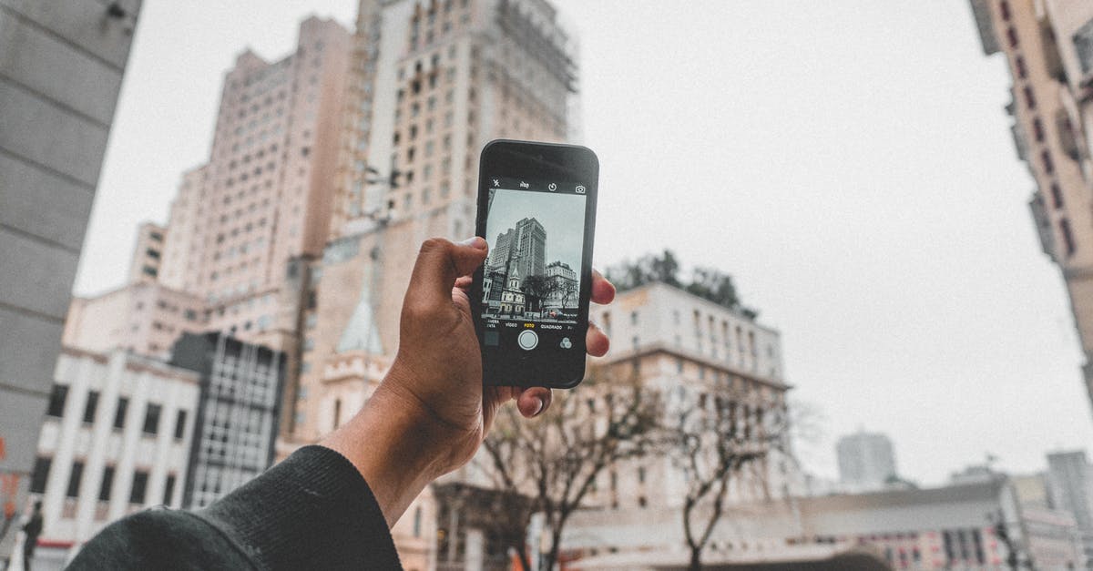 What is the location of photo used for Windows 10 lock screen? [duplicate] - Crop anonymous person taking pictures of modern buildings located on urban street by using mobile phone during autumn cold day