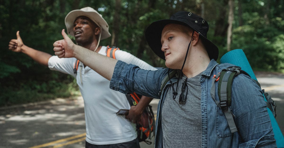What is the PET-3 road like between El Cruce and Tikal? - Young multiracial male backpackers in panama hats with hiking equipment standing with thumbs up on roadway against forest and looking away What is the PET-3 road like between El Cruce and Tikal? - Young multiracial male backpackers in panama hats with hiking equipment standing with thumbs up on roadway against forest and looking away