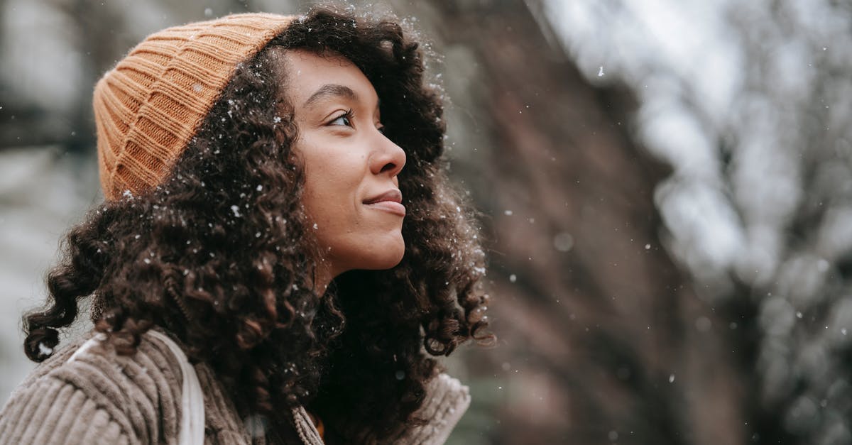 what kind of hat would be most effective for reducing heat? - Side view of dreamy young black female in knitted hat looking up in town on snowy day what kind of hat would be most effective for reducing heat? - Side view of dreamy young black female in knitted hat looking up in town on snowy day