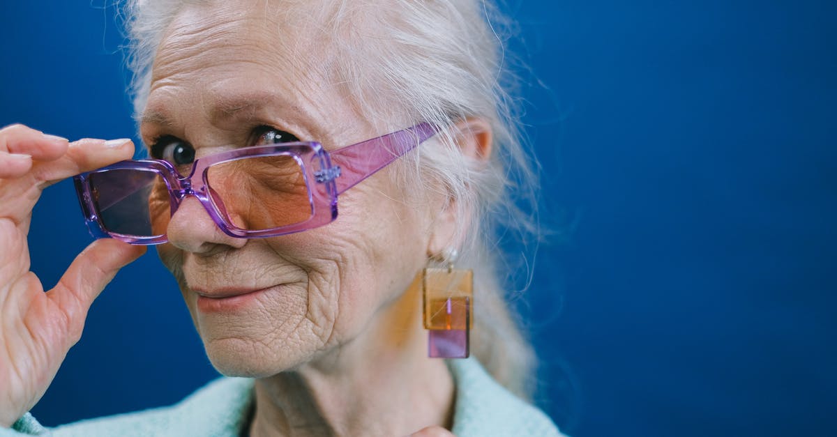 What kind of ID does the US accept when visiting bars or drinking age events? - Portrait of elegant smiling gray haired elderly female wearing purple sunglasses and earrings looking at camera against blue background What kind of ID does the US accept when visiting bars or drinking age events? - Portrait of elegant smiling gray haired elderly female wearing purple sunglasses and earrings looking at camera against blue background