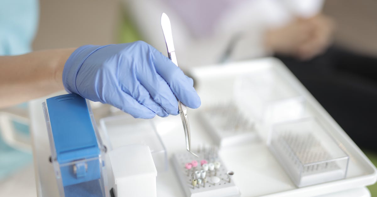 What measures to take in Scotland on unclear 2-day PCR test - Anonymous medical specialist in latex gloves using forceps to take detail from plastic container while working in modern clinic What measures to take in Scotland on unclear 2-day PCR test - Anonymous medical specialist in latex gloves using forceps to take detail from plastic container while working in modern clinic