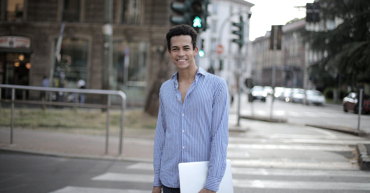What organizations give computer science PhD students travel grants? - Positive ethnic guy in shirt holding laptop and smiling at camera while standing on city pedestrian crosswalk in city center What organizations give computer science PhD students travel grants? - Positive ethnic guy in shirt holding laptop and smiling at camera while standing on city pedestrian crosswalk in city center