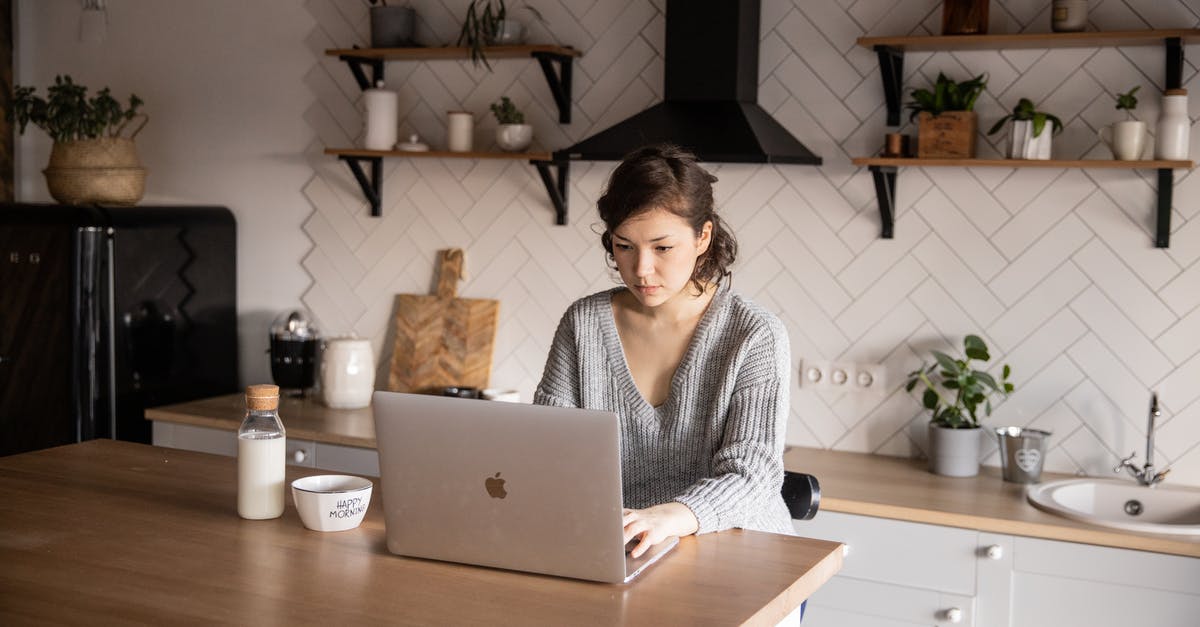 What popular western web services don't work in mainland China? - Content young woman browsing laptop in modern kitchen What popular western web services don't work in mainland China? - Content young woman browsing laptop in modern kitchen