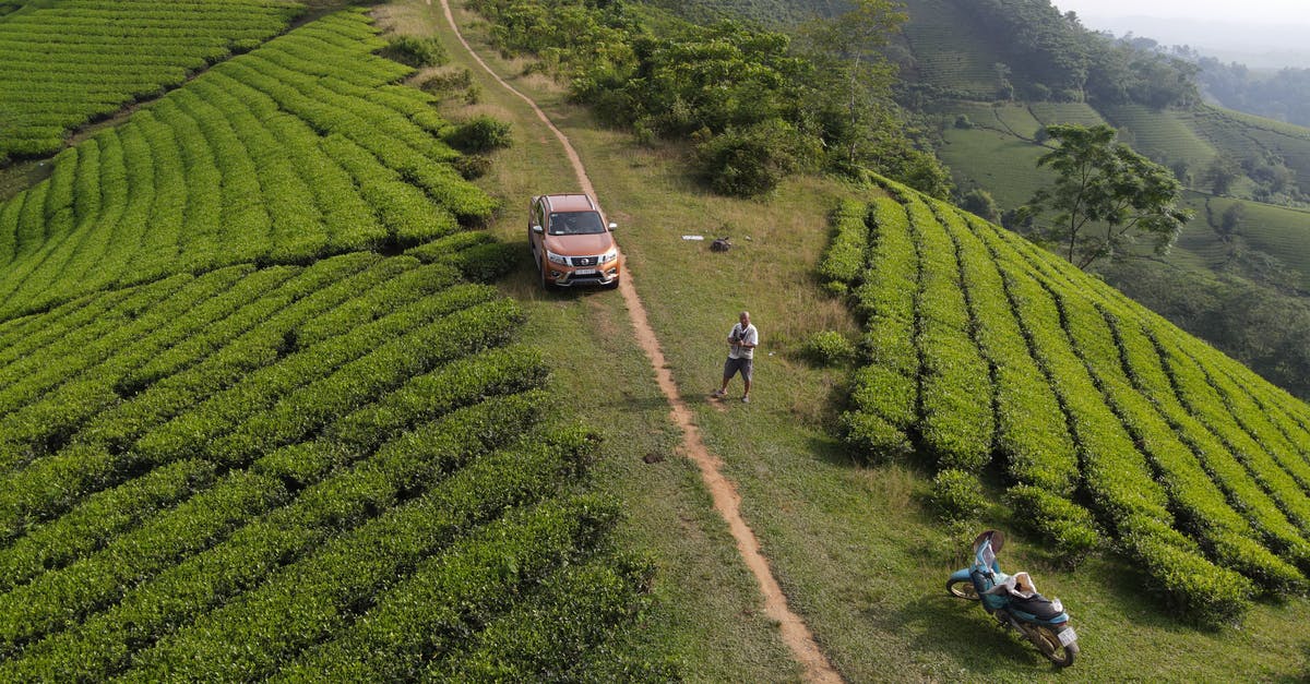 What should I bring for a lightweight motorcycle trip across Vietnam? [closed] - Drone view of SUV car and motorcycle parked near unrecognizable male traveler standing on green hill with tea plantations during trip in Vietnam