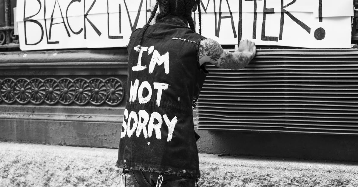 What should I do if I get caught by corrupt police in Ukraine but never want to pay? - Back view of unrecognizable tattooed guy standing on street in front of banner with Black Lives Matter inscription