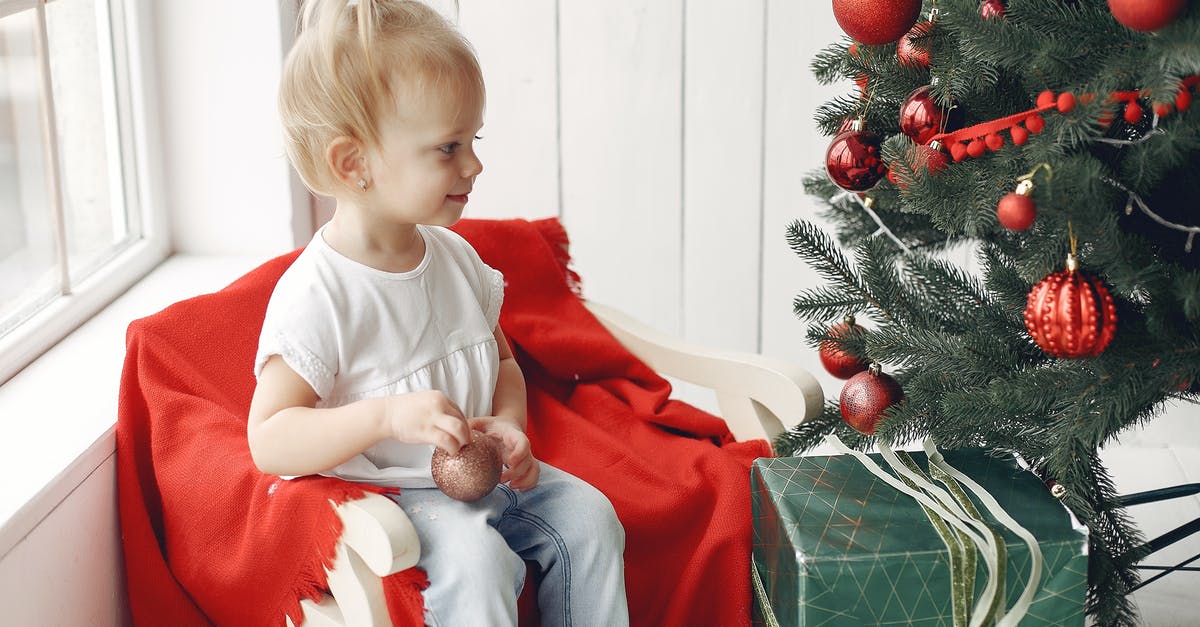 What should I do stay a little bit more or going abroad after my internship? [closed] - Boy in Red Crew Neck T-shirt Sitting on Green Box Beside Green Christmas Tree