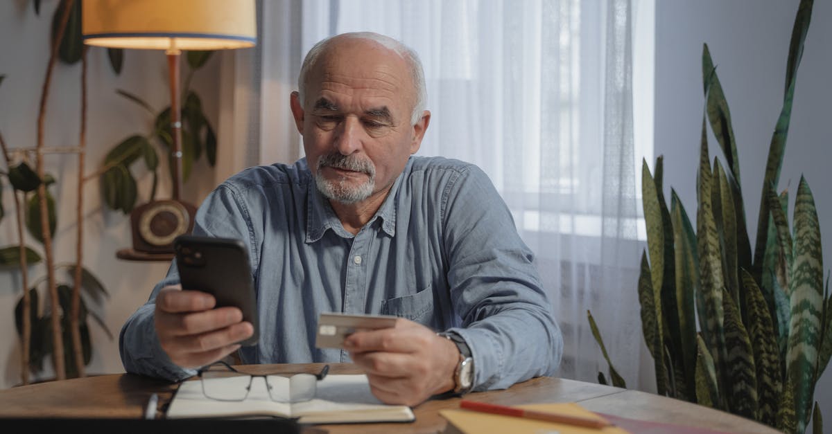 What should I do with an old NEXUS card? - An Elderly Man Using His Mobile Phone while Holding a Credit Card What should I do with an old NEXUS card? - An Elderly Man Using His Mobile Phone while Holding a Credit Card
