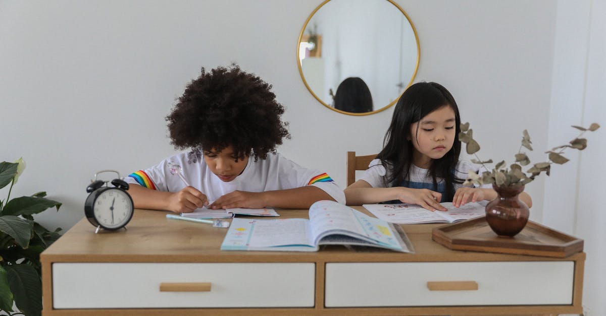 What should I think of and prepare when flying with kids? - Concentrated multiracial girls sitting at table with notebooks and doing homework in cozy room What should I think of and prepare when flying with kids? - Concentrated multiracial girls sitting at table with notebooks and doing homework in cozy room