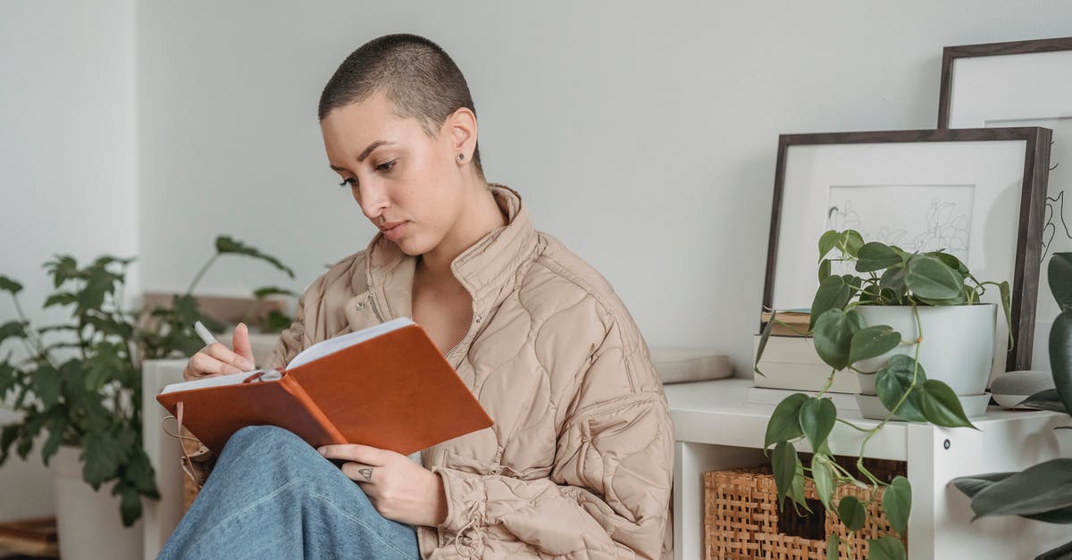 What should you do with your house keys while traveling a short time? - Attentive woman writing in diary at home What should you do with your house keys while traveling a short time? - Attentive woman writing in diary at home