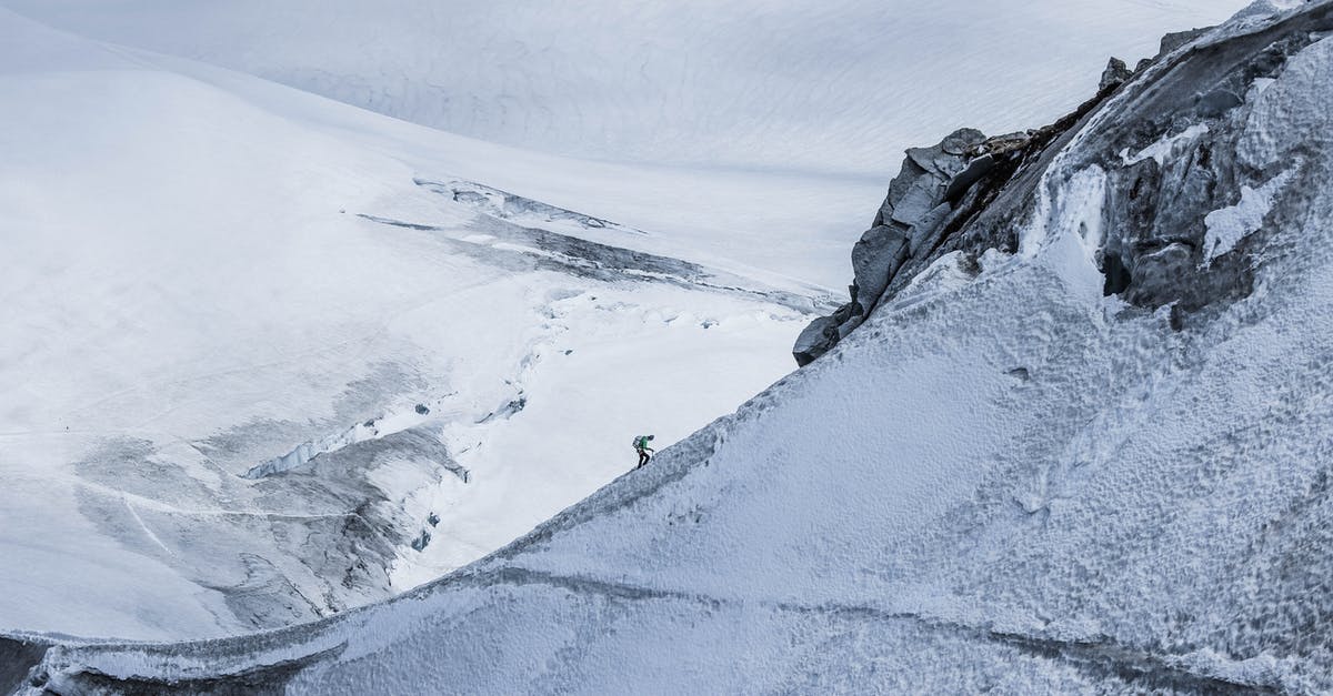 What sightseeing activities are available in winter in the Rocky Mountains? [closed] - From above distant alpinist on snowy rough mountain slope against frozen spacious mountainous valley in daylight