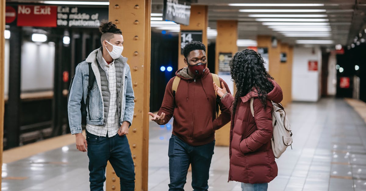 What time to reach Italian Train stations to board train(s)? - Multiracial group of friends with backpacks wearing protective masks looking at each other while standing on subway station during meeting What time to reach Italian Train stations to board train(s)? - Multiracial group of friends with backpacks wearing protective masks looking at each other while standing on subway station during meeting