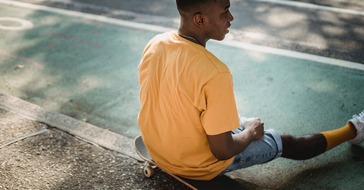 What time to reach Italian Train stations to board train(s)? - Trendy black guy sitting on skateboard after workout in sunlight What time to reach Italian Train stations to board train(s)? - Trendy black guy sitting on skateboard after workout in sunlight