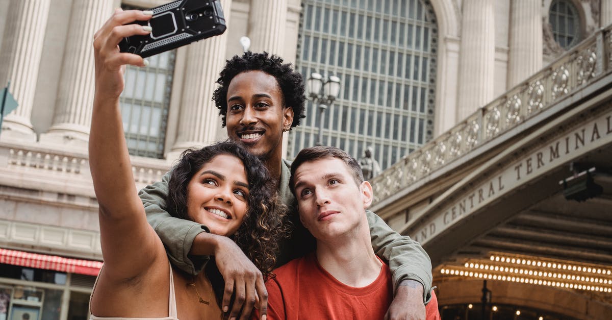 What to do about bad photo on issued US passport - Positive multiethnic friends taking selfie on modern smartphone near railway station building What to do about bad photo on issued US passport - Positive multiethnic friends taking selfie on modern smartphone near railway station building