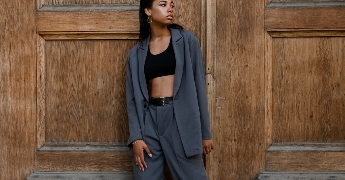 What to wear in Russia - Woman in Black Tank Top and Gray Blazer Standing Beside Brown Wooden Wall What to wear in Russia - Woman in Black Tank Top and Gray Blazer Standing Beside Brown Wooden Wall