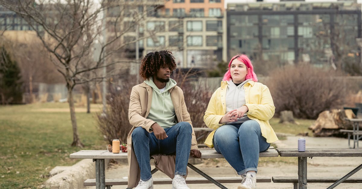 When boarding a full plane, how can I guarantee that I can keep my handheld baggage with me? - Multiethnic couple sitting on table in park When boarding a full plane, how can I guarantee that I can keep my handheld baggage with me? - Multiethnic couple sitting on table in park
