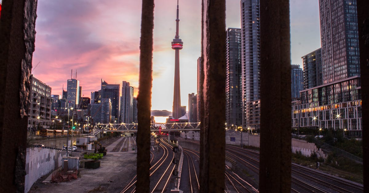 When to visit both the Schengen area and the UK, which visa should be obtained first? - Through railing bars scenery of evening Toronto city with contemporary glass skyscrapers at sundown When to visit both the Schengen area and the UK, which visa should be obtained first? - Through railing bars scenery of evening Toronto city with contemporary glass skyscrapers at sundown