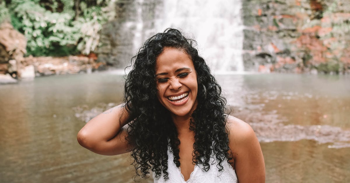 When traveling outside scandinavia while being intolerant to lactose, how can I still enjoy a latte? [closed] - Laughing African American female with closed eyes standing near river against streaming waterfall falling from rocky cliff in wild nature