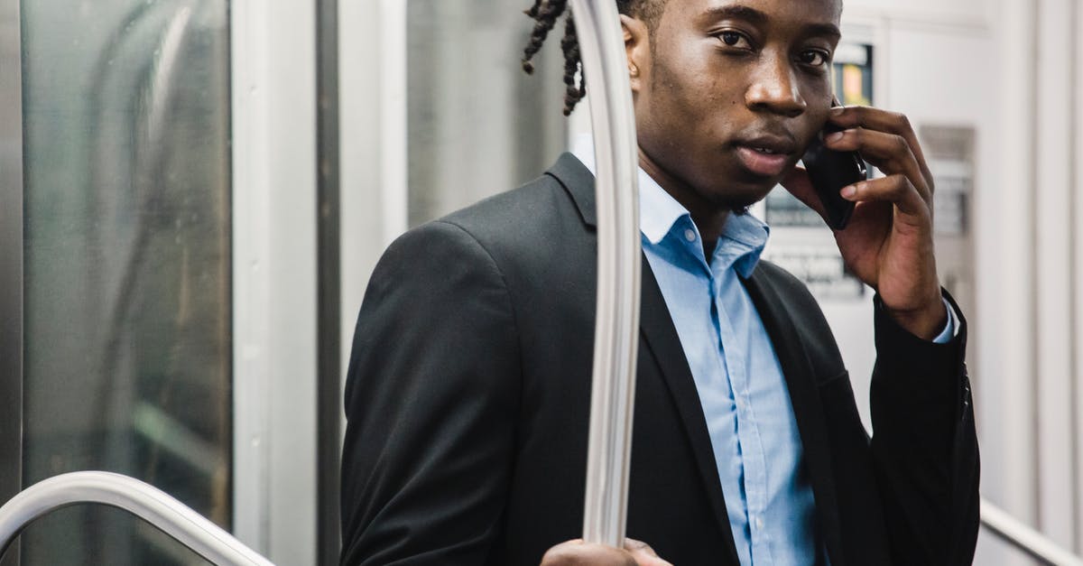 When using rail passes in Germany, can I use it in "urban trains" as well? (U-bahn, S-bahn) - Young handsome African American male in formal suit making phone call on smartphone while traveling by commuter train
