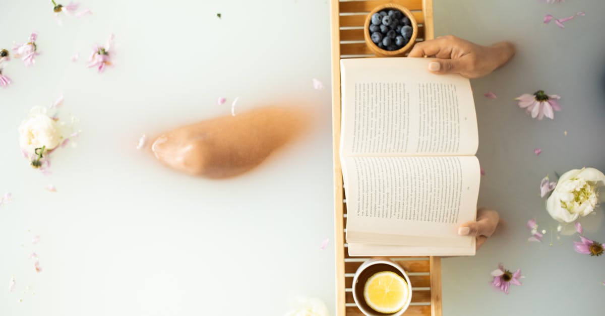 Where's the trailhead to Blueberry Hill? - Top view of crop unrecognizable lady in white water in bathtub with fresh colorful flower petals with wooden tray with cup of tea with lemon and blueberries while reading book Where's the trailhead to Blueberry Hill? - Top view of crop unrecognizable lady in white water in bathtub with fresh colorful flower petals with wooden tray with cup of tea with lemon and blueberries while reading book