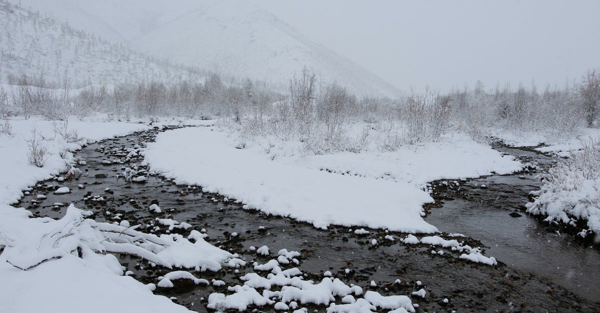 Where are these 3 white flagstaffs in front of a commemorative stone, river and valleys? [closed] - River in snowy mountainous area