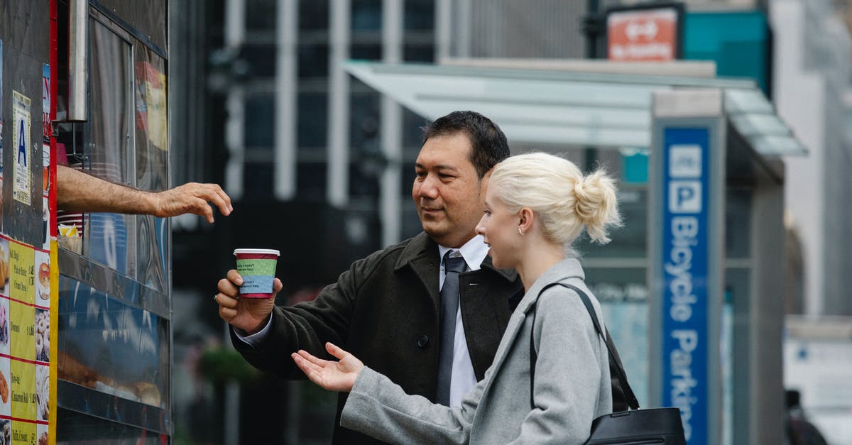 Where can I buy a cup of 'cat poo' coffee (Kopi Luwak) in Melbourne? - Side view of young female manager with ethnic male colleague in formal clothes buying takeaway coffee from booth on city street during break Where can I buy a cup of 'cat poo' coffee (Kopi Luwak) in Melbourne? - Side view of young female manager with ethnic male colleague in formal clothes buying takeaway coffee from booth on city street during break