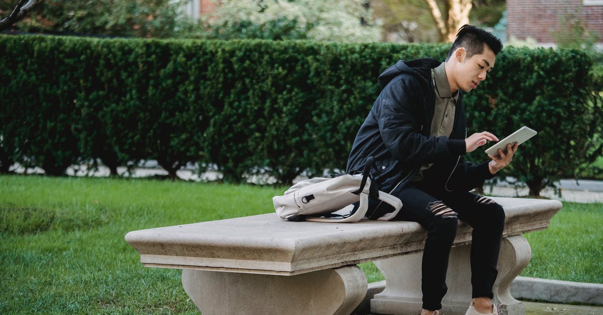 Where can I find the GWR web chat? - Full body of young focused Asian male in casual wear sitting on bench in park and browsing internet on tablet Where can I find the GWR web chat? - Full body of young focused Asian male in casual wear sitting on bench in park and browsing internet on tablet