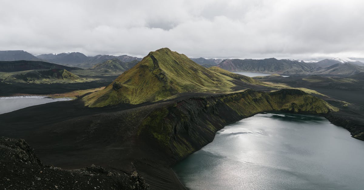 Where can I see volcanic rivers in Iceland? - Drone view of majestic calm lake surrounded by volcanic mountain ranges in Iceland Where can I see volcanic rivers in Iceland? - Drone view of majestic calm lake surrounded by volcanic mountain ranges in Iceland