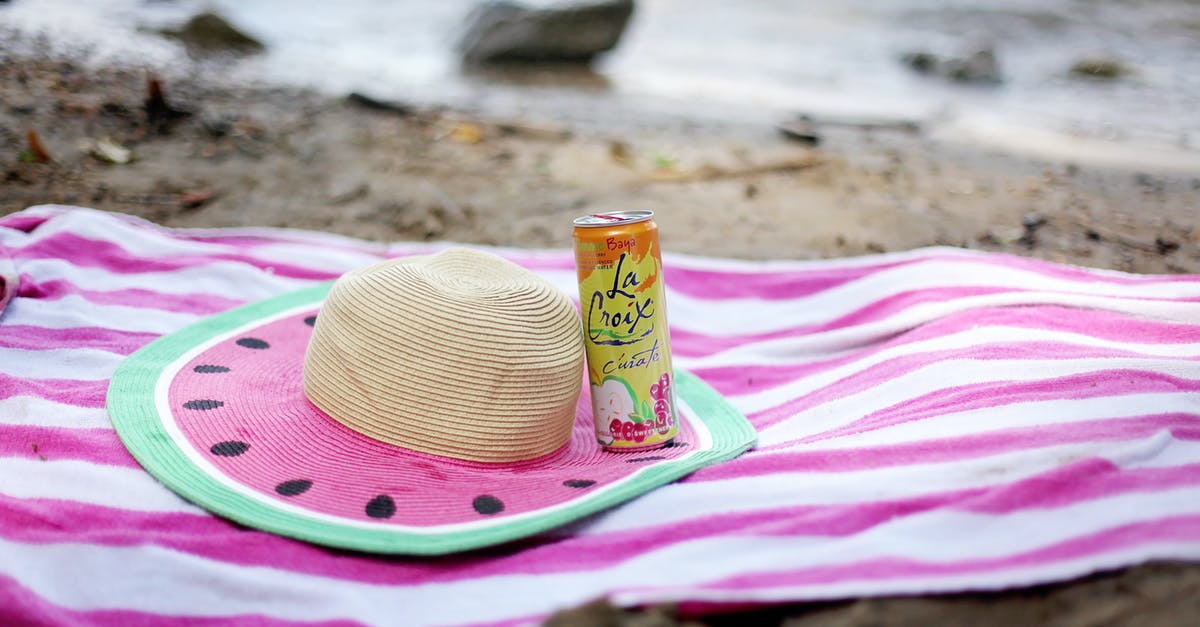 Where can I travel with a Norwegian Convention Travel Document? - Striped towel spread on sandy beach with straw hat and juice can