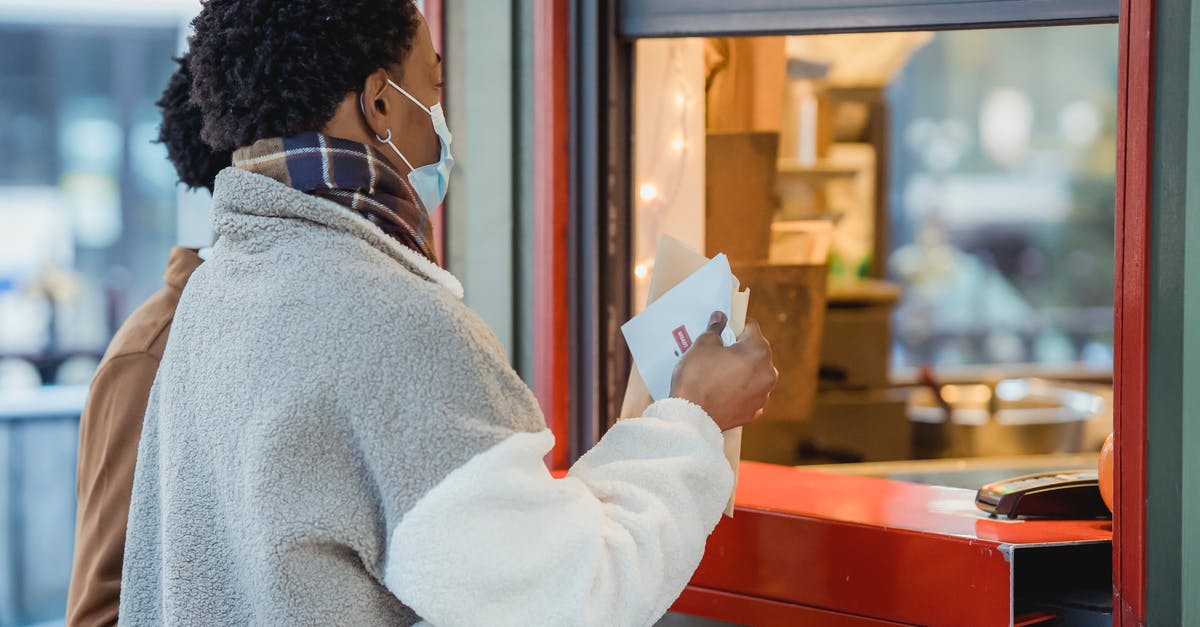 Where can you safely store your belongings in order to travel? [closed] - Side view of African American male couple in protective masks standing near window of store while ordering food on street on blurred background