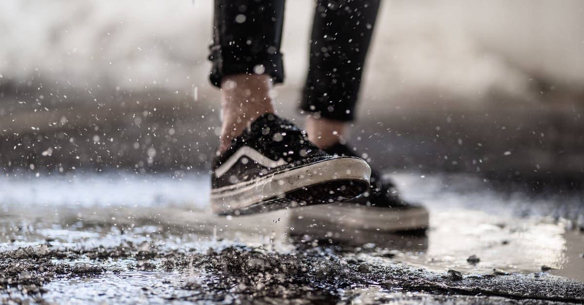 Where do I drop off and pick up a foot passenger in Calais (P&O)? - Crop person walking through puddles on asphalt Where do I drop off and pick up a foot passenger in Calais (P&O)? - Crop person walking through puddles on asphalt
