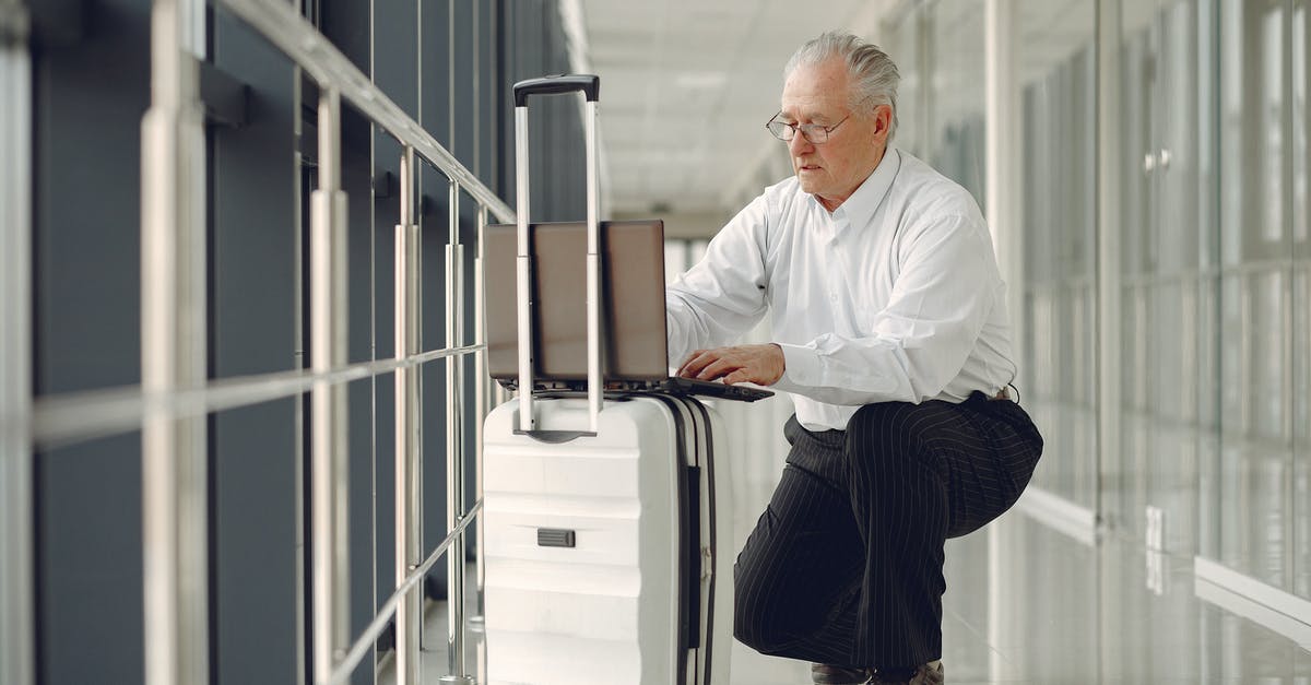 Where do you get an Australian outgoing passenger card if checking in online and only having hand luggage? - Full length of focused mature male in formal wear using laptop on baggage while having semisitting position in airport corridor Where do you get an Australian outgoing passenger card if checking in online and only having hand luggage? - Full length of focused mature male in formal wear using laptop on baggage while having semisitting position in airport corridor