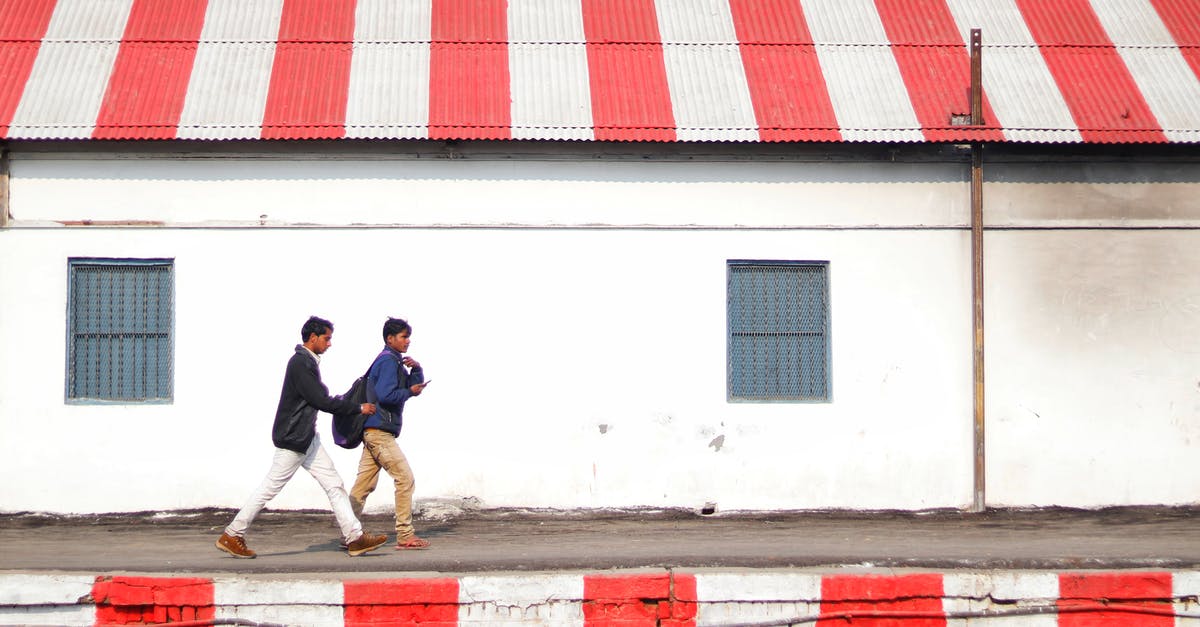Where does one apply for 6 month Indian tourist visa? - Side view of young Asian guys walking on platform painted with white and red stripes along shabby stone building with striped white and red roof on daytime Where does one apply for 6 month Indian tourist visa? - Side view of young Asian guys walking on platform painted with white and red stripes along shabby stone building with striped white and red roof on daytime