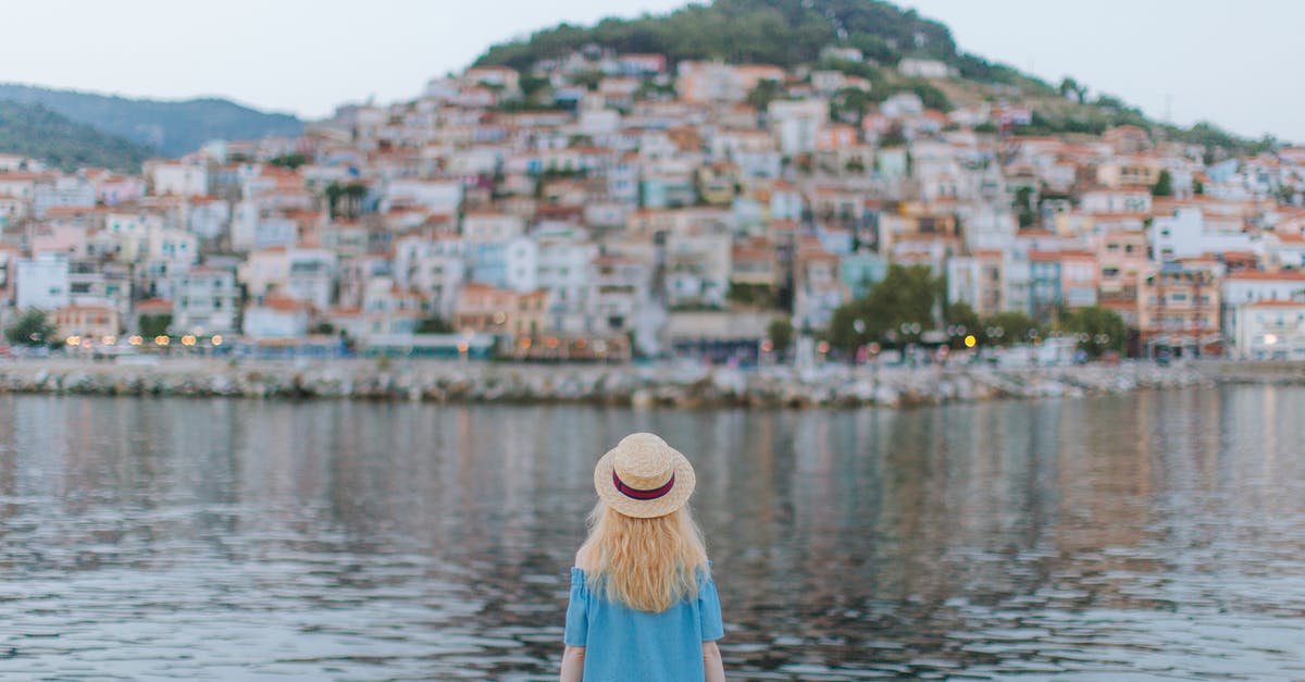 Where in the world is this harbour town? - Back View of Woman in Blue Dress Sitting on the Shore Where in the world is this harbour town? - Back View of Woman in Blue Dress Sitting on the Shore