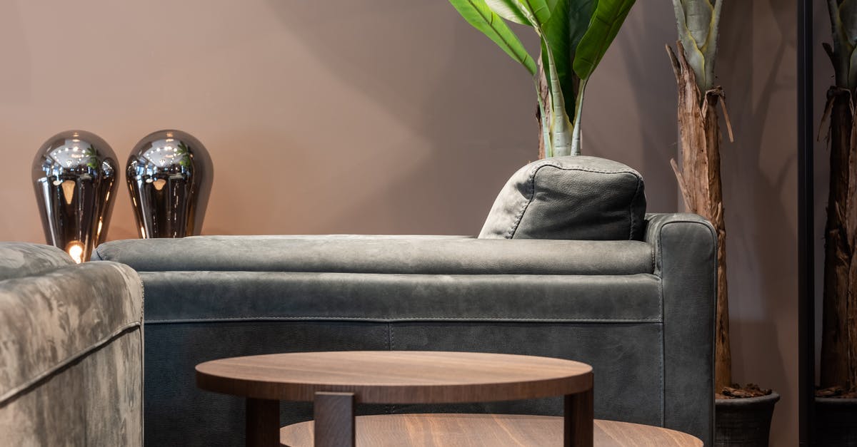 Where is the best place to relax after arriving in KUL [closed] - Comfortable couch near round complex table in modern room with potted green plants