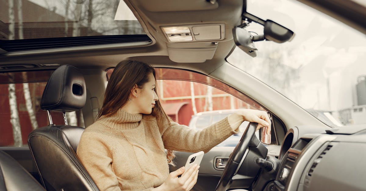 Where is the largest road network that shares a landmass with, but is disconnected from, a larger ('main') road network? [closed] - Adult woman sitting in car and using smartphone