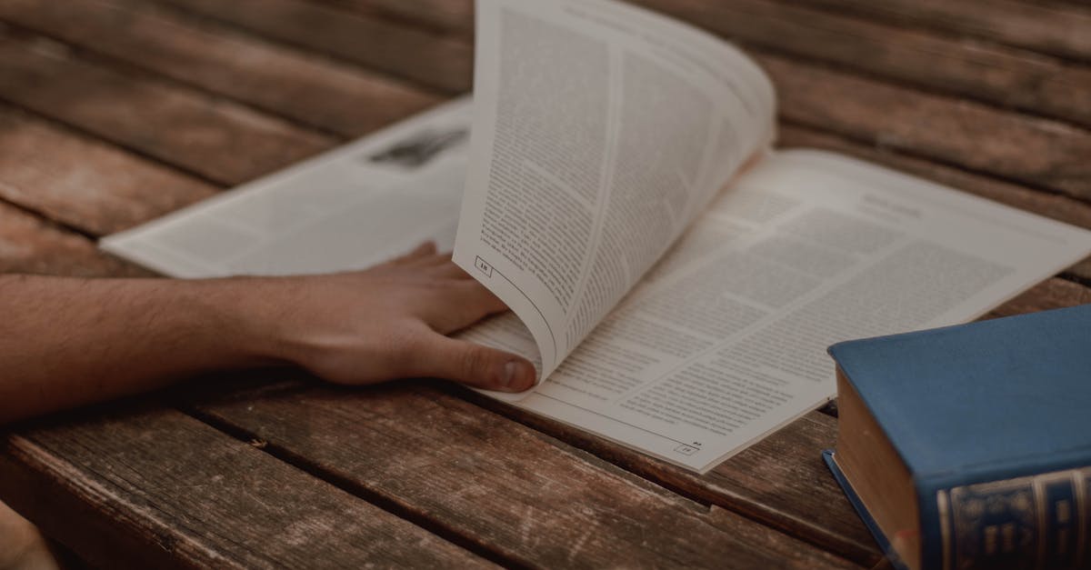 Where is the passport book number and what is the difference from the passport number? - From above of crop unrecognizable male reading magazine with text in columns near old book