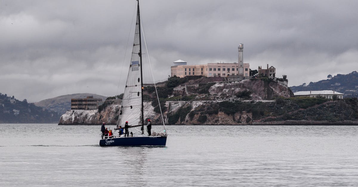 Where is this castle? - White and Blue Boat on Sea Near Brown Concrete Building Under Gray Sky Where is this castle? - White and Blue Boat on Sea Near Brown Concrete Building Under Gray Sky