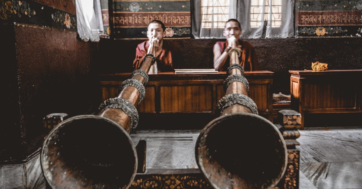 Where is this huge indoor waterfall? - Man Tibetan musicians playing dungchen instrument in temple Where is this huge indoor waterfall? - Man Tibetan musicians playing dungchen instrument in temple