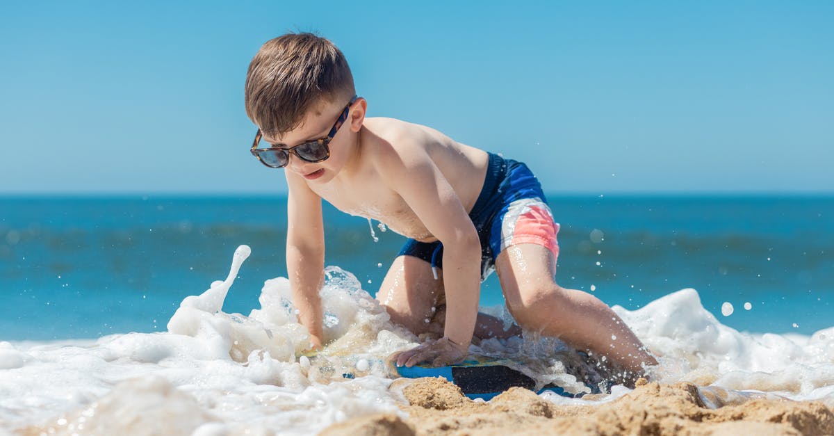 Where is this sand boarding in Oregon? [closed] - A Boy in Blue Shorts Sitting on Beach Shore