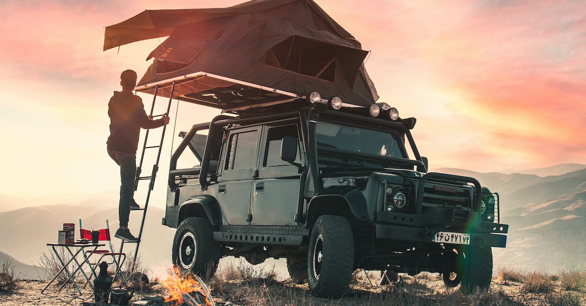 Where is wild camping possible in Europe? - Back view of crop anonymous male traveler watching sunset during camping in mountains and climbing upstairs to tent located on roof of contemporary offroader Where is wild camping possible in Europe? - Back view of crop anonymous male traveler watching sunset during camping in mountains and climbing upstairs to tent located on roof of contemporary offroader