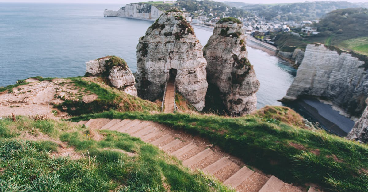 Where on Earth is this Win10 lock screen image from, with a stone town in a rock crevice? [duplicate] - From above of stair surrounded by grass leading to ocean washing rocky cliff on shore near coastal town in nature