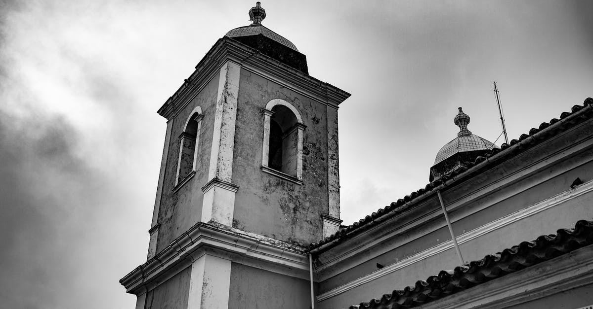 Where on Earth is this Win10 lock screen image from, with a stone town in a rock crevice? [duplicate] - Old church tower under gloomy sky