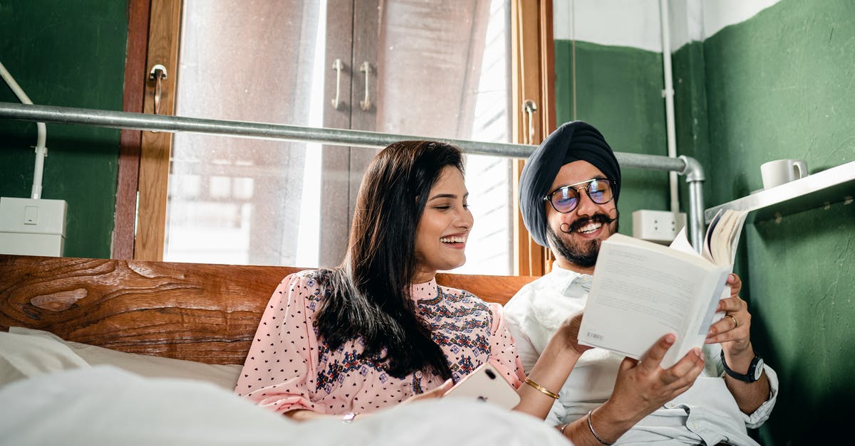 Where to book Indian train tickets online? - Happy couple reading book and communicating cheerfully at home Where to book Indian train tickets online? - Happy couple reading book and communicating cheerfully at home