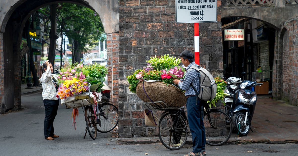 Where to find a bike to hire / buy / borrow in Southern Spain - Side view of male in casual clothes standing near bicycle with baskets of colorful flowers of vendor and buying flowers from woman on town street Where to find a bike to hire / buy / borrow in Southern Spain - Side view of male in casual clothes standing near bicycle with baskets of colorful flowers of vendor and buying flowers from woman on town street
