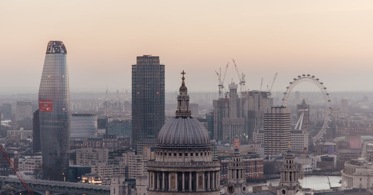 Where to find old buildings: taverns, castles, cathedrals, etc to visit while in London [closed] - Cityscape of London with historic St Pauls cathedral with dome located near modern multistory skyscrapers and famous observation wheel near river