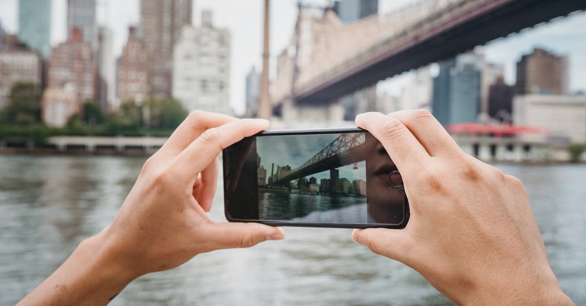 Where was this photo of a bridge taken? [duplicate] - Crop unrecognizable traveler taking photo of modern suspension bridge in city using mobile phone in daytime