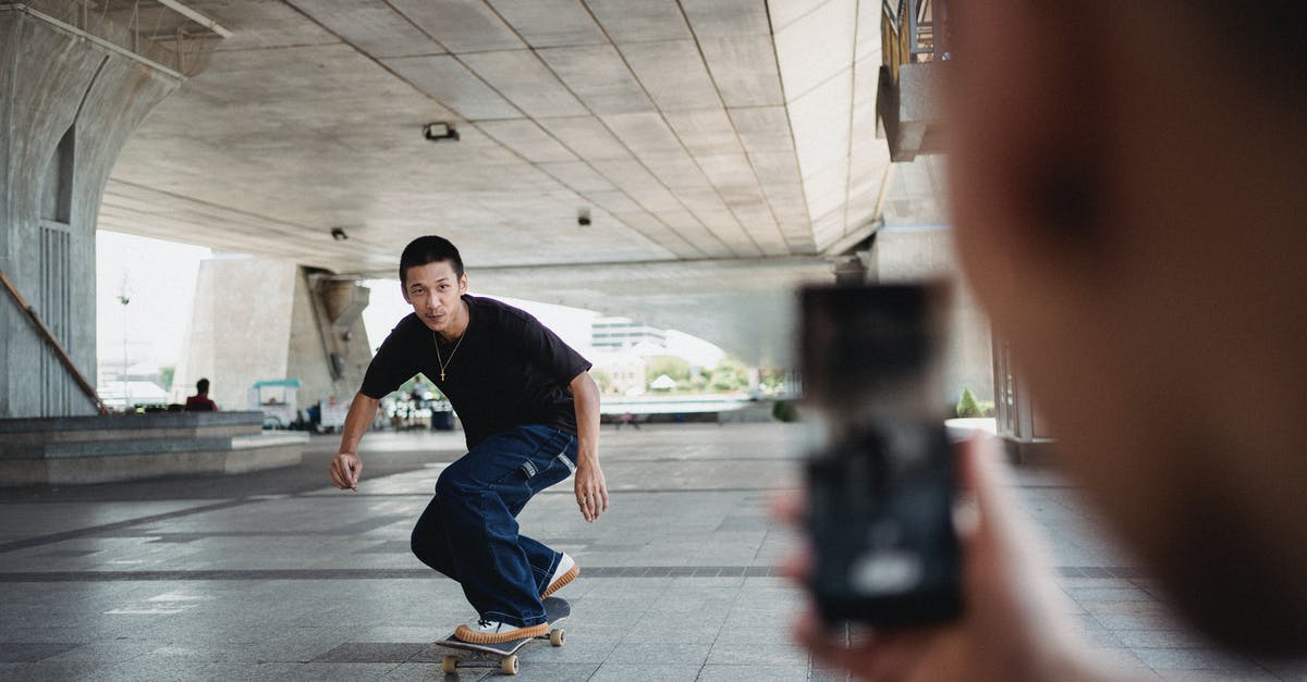 Where was this photo of a bridge taken? [duplicate] - Unrecognizable person taking picture on smartphone of Asian male friend riding skateboard under transport bridge in city center