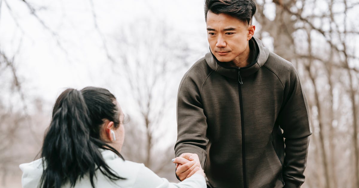 Which consulate will give me the longest Schengen visa? - Calm Asian man in sportswear giving hand to unrecognizable female with dark hair in earphones in autumn park in daytime Which consulate will give me the longest Schengen visa? - Calm Asian man in sportswear giving hand to unrecognizable female with dark hair in earphones in autumn park in daytime