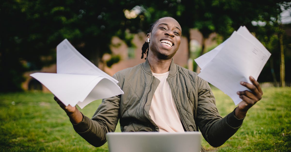 Which countries allow to work remotely on visitor visas? [closed] - Happy African American man holding sheets of paper in front of laptop